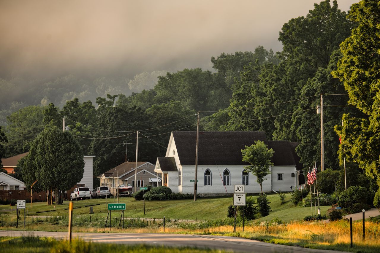 White church and houses in a quiet American small town with misty green hills and golden grass