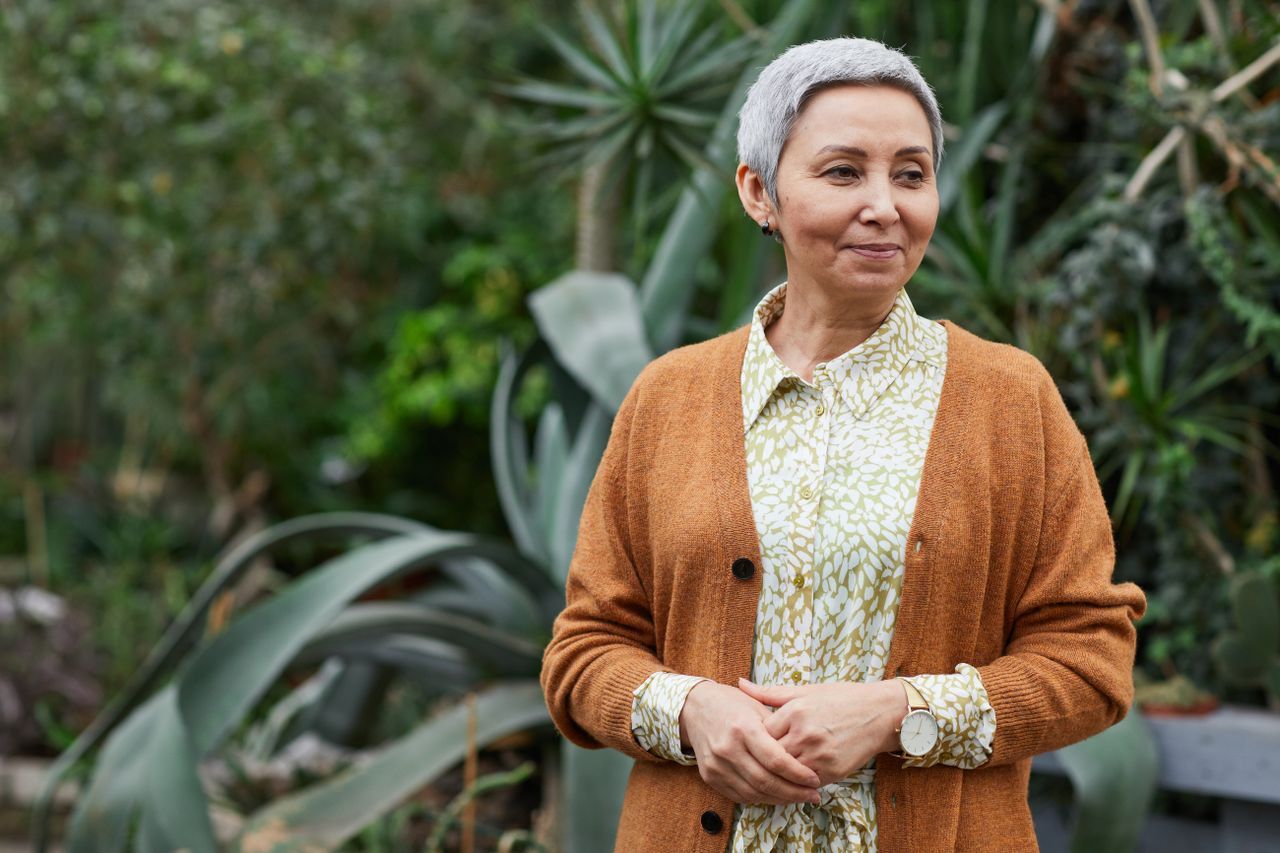 Senior woman with short gray hair smiling gracefully in a garden