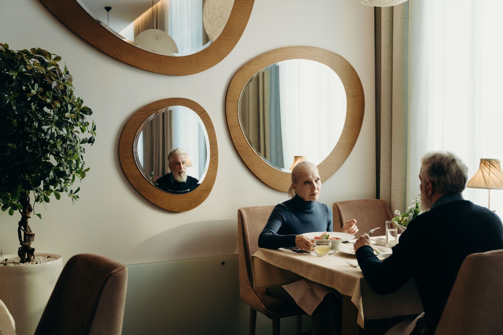 Older couple having dinner at a restaurant table with circular mirrors on the wall