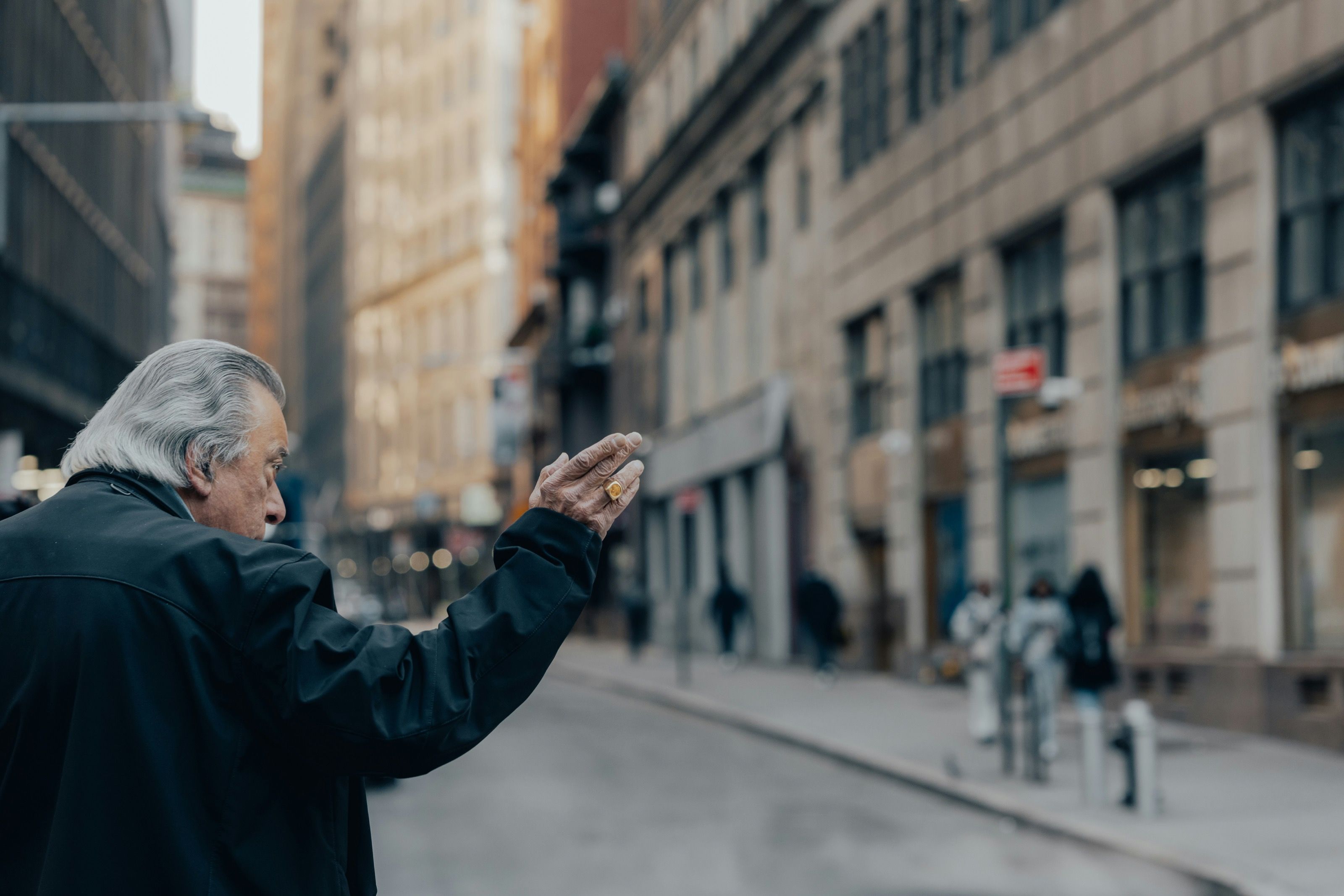 Older man gesturing on a quiet city street