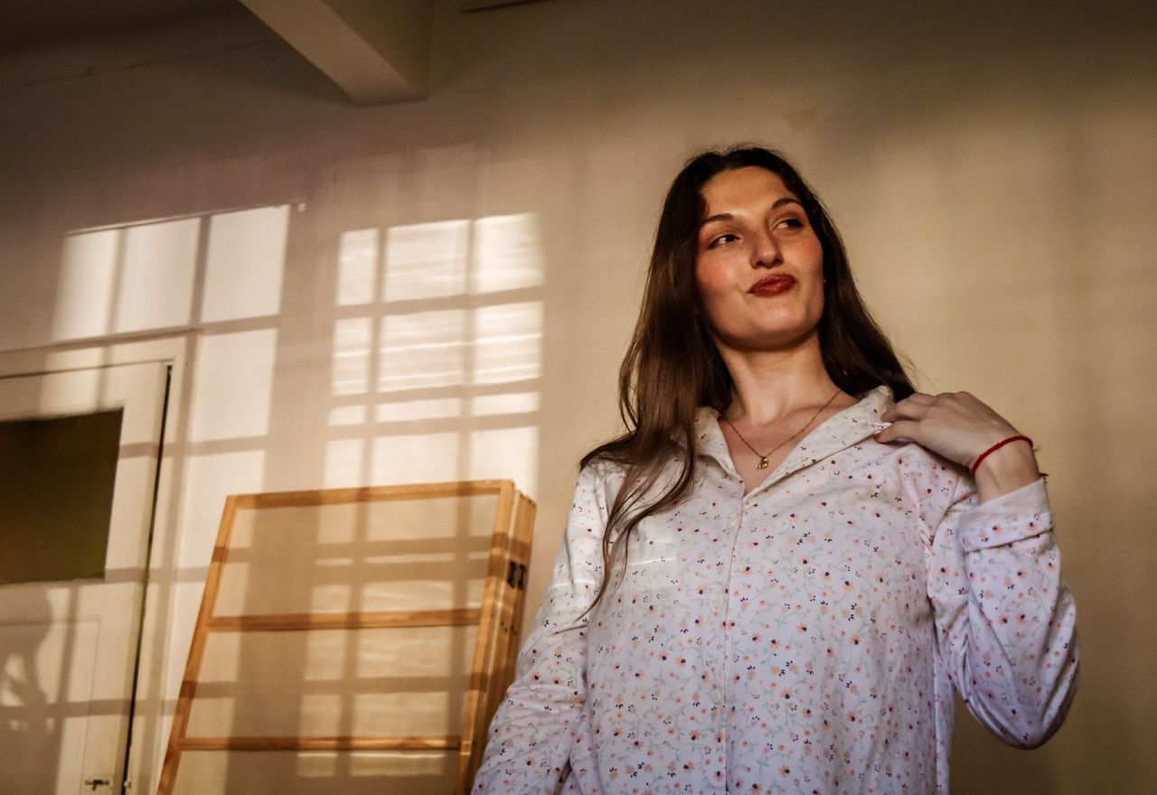 Woman over 50 standing near a window in a sunlit room with calm self-possession