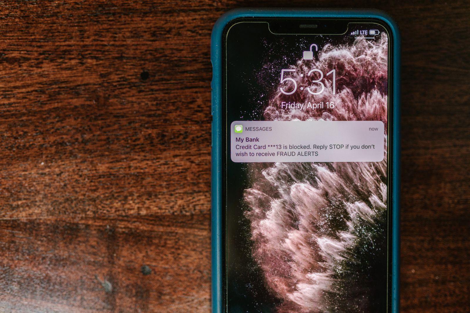 Smartphone displaying a fraud alert message on a wooden surface
