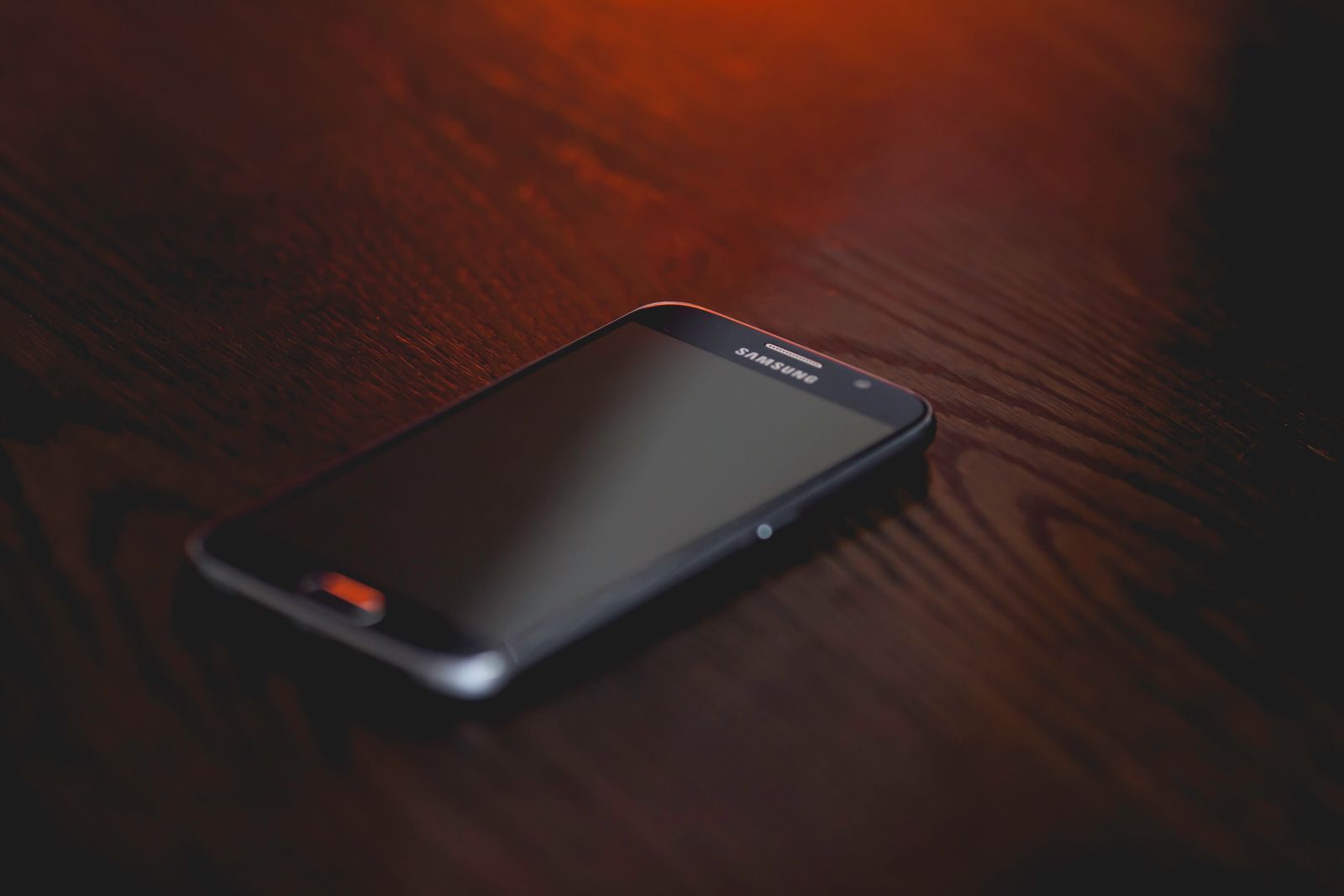 Smartphone resting on a dark wooden surface with moody ambient light