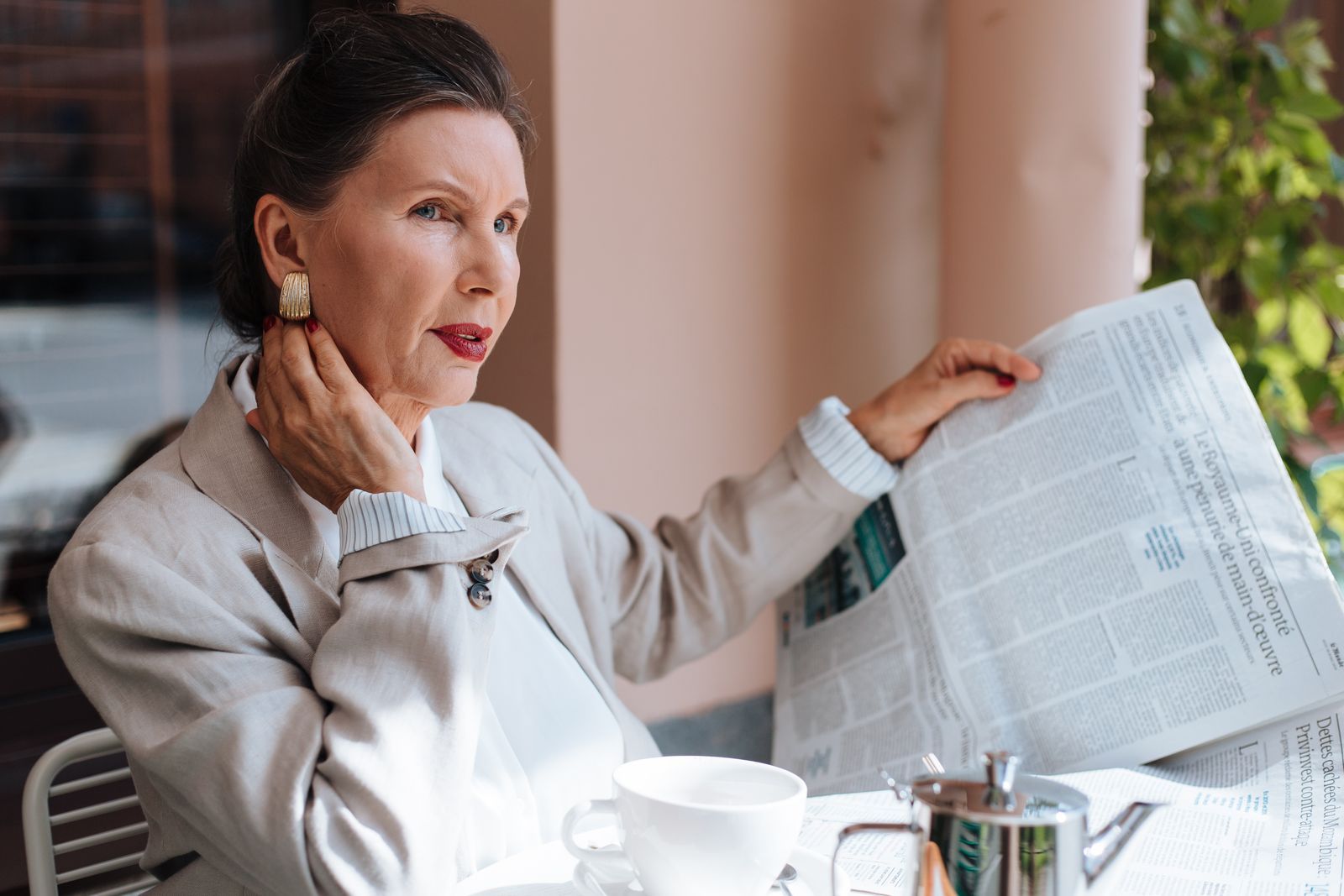Senior woman reading a newspaper with coffee on a sunny morning, content in her own space