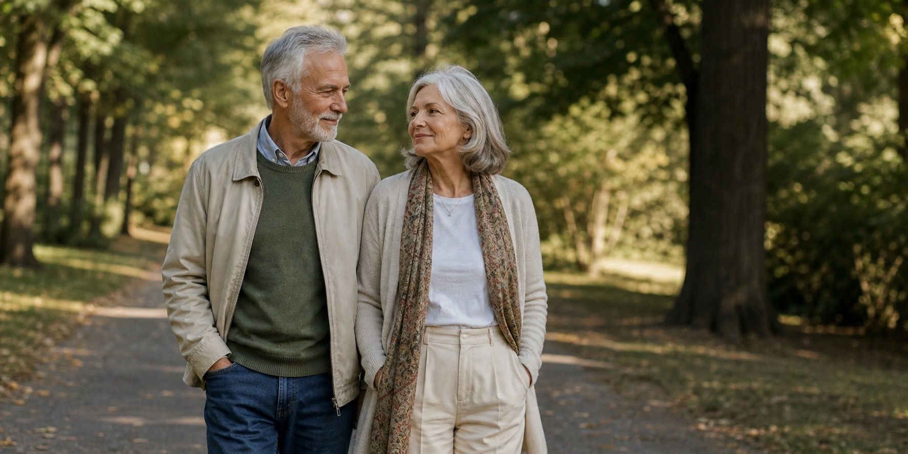 Two people over 60 walking side by side along a quiet tree-lined path