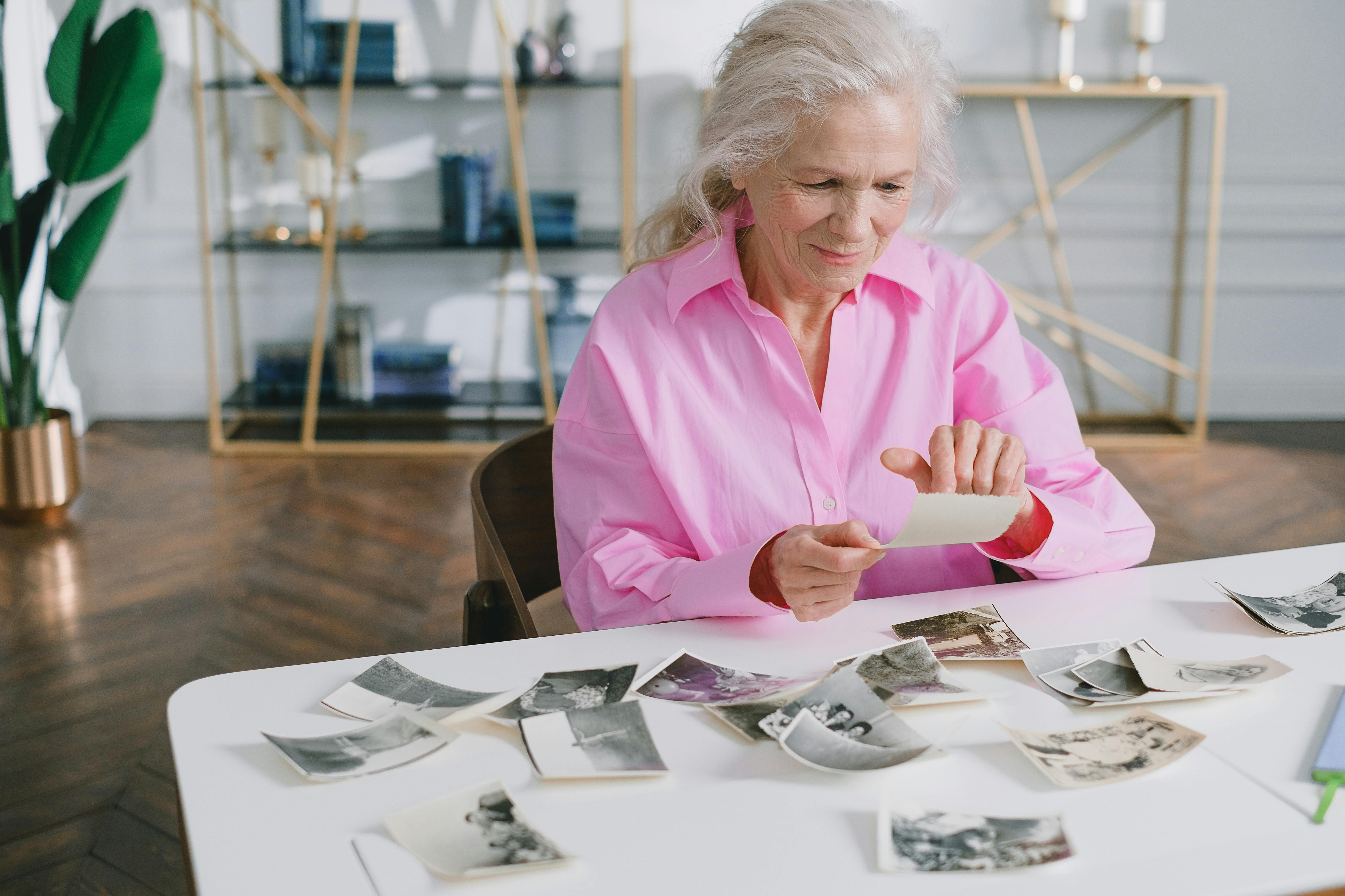 Older woman sorting printed photos at a table at home