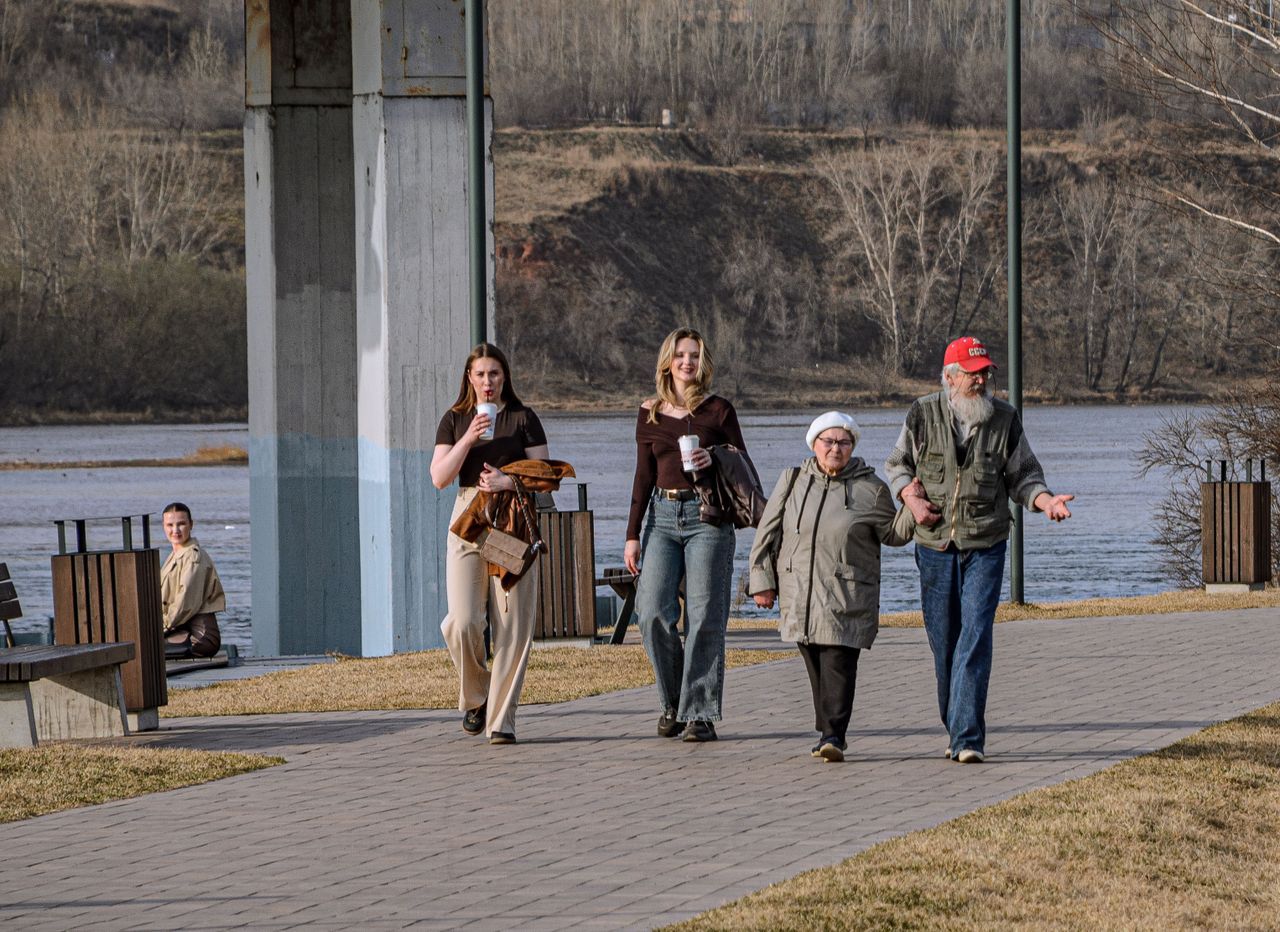Small group of adults walking together along a riverside path on a spring morning